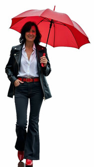 Een lachende dame in Anna Montana Finja flared jeans in het zwart, gestyled met een leren jack en rode accessoires. 
